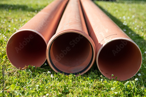 Orange plastic sewer pipes in the green grass