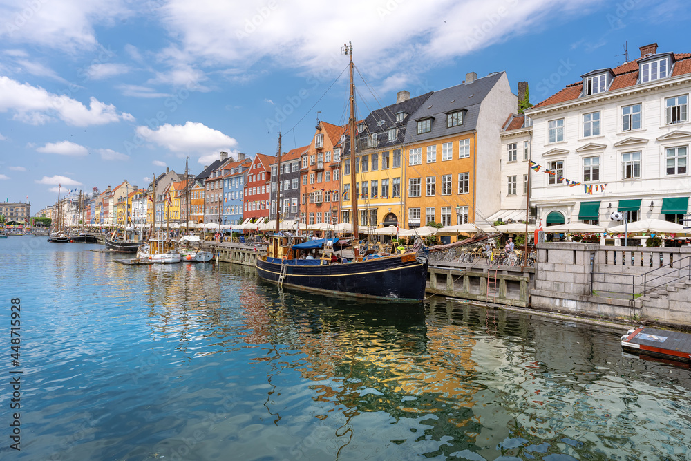 Panorama view of Nyhawn, the colorful houses next to the old port. Tourist visiting restaurants, cafes and ships in the canal. The most important sightseeing spot in Copenhagen, Denmark.