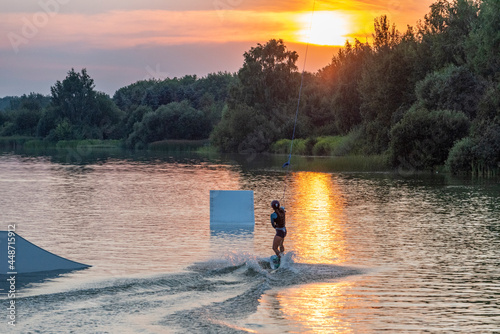 Man water wakeboarding skiing at sunset.