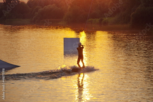 Man water wakeboarding skiing at sunset.