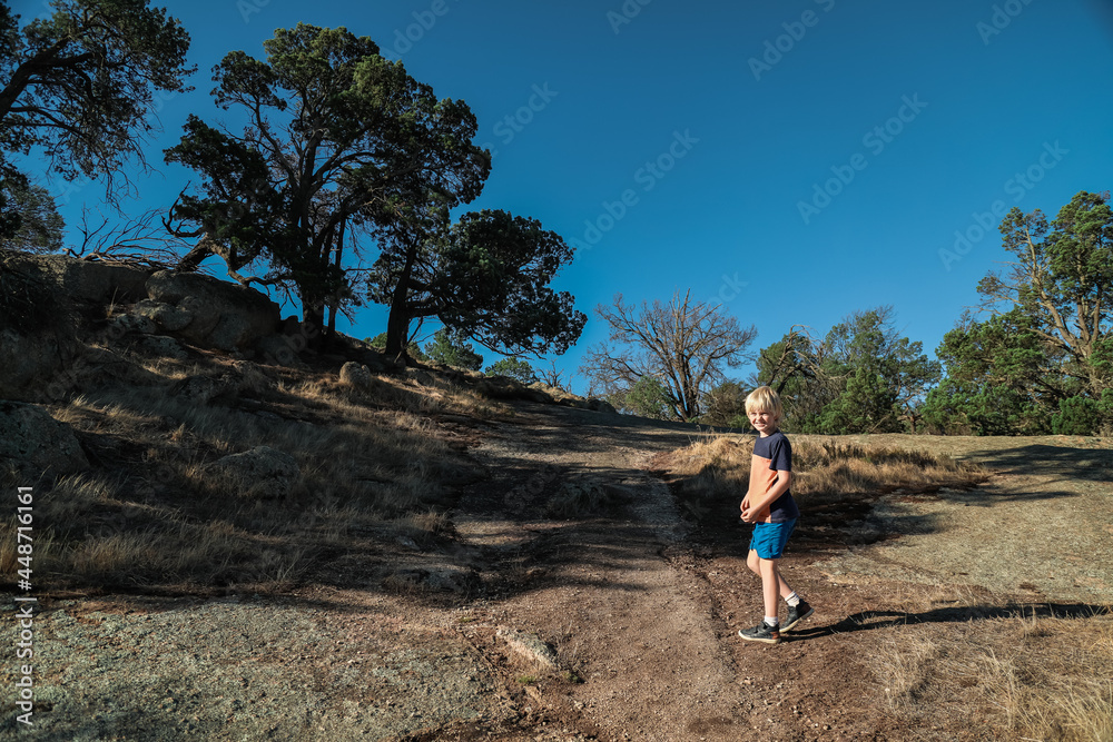 Boy exploring rocky hill top at the Terrick Terrick National Park near Mitiamo, Victoria Australia