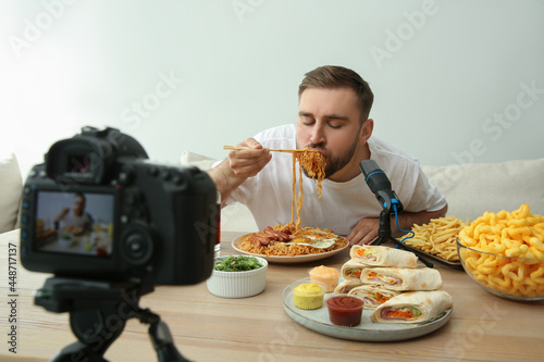 Food blogger recording eating show on camera against light background. Mukbang vlog