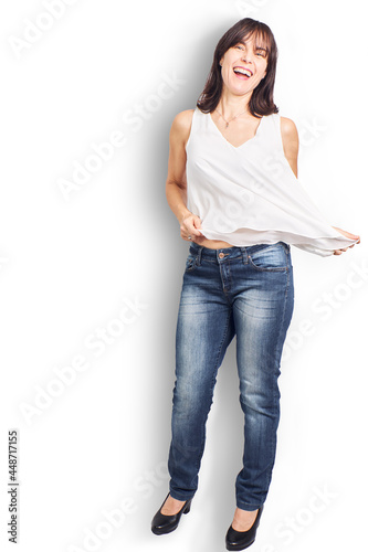 Beautiful woman in her fifties with white blouse and jeans on a white background having a graceful pose and a cheerful look and a smile