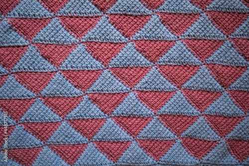 The canvas is crocheted in pink blue. The pattern of triangles is made in the style of Tunisian knitting.
