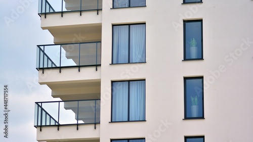 Modern white facade of a residential building with large windows. View of modern designed concrete apartment building.