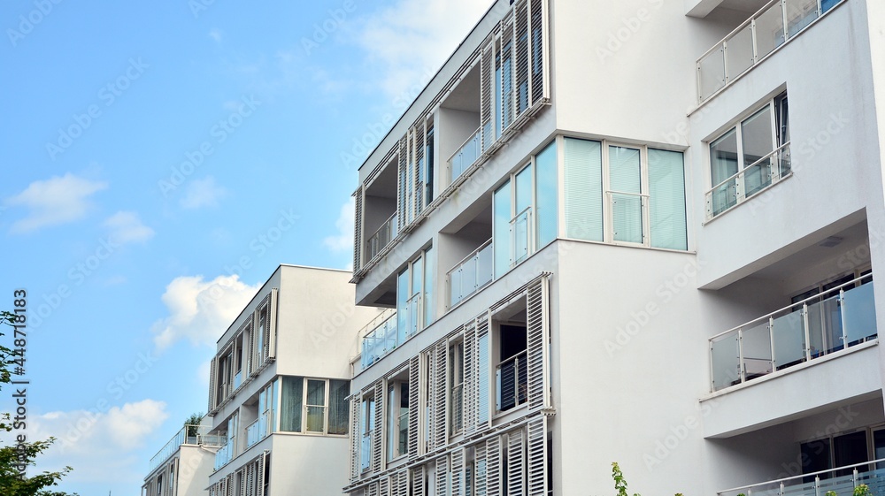 Modern white facade of a residential building with large windows. View of modern designed concrete apartment building.
