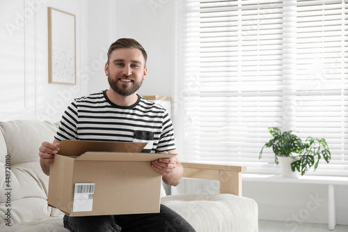 Happy young man with parcel at home