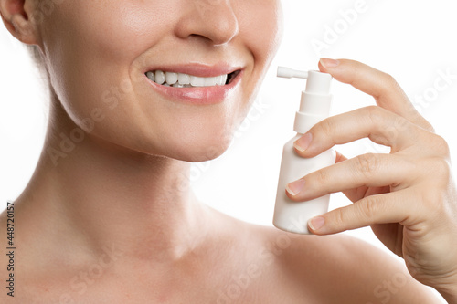 Woman is using spray for sore throat relief