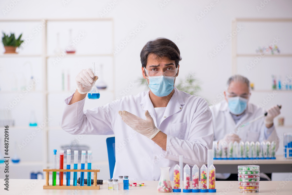 Two male chemists in drugs synthesis concept at the lab Two male chemists in drugs synthesis concept at the lab