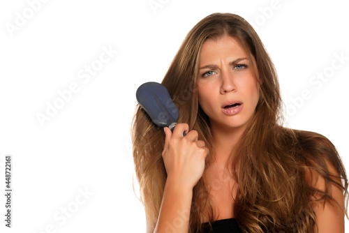 Young nervous woman brusing her hair with hairbrush photo