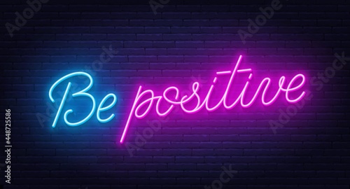 Be positive neon sign on brick wall background.