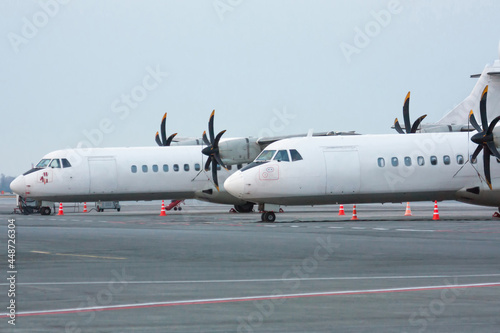 Two white passenger turboprop aircrafts on the airport apron © Dushlik