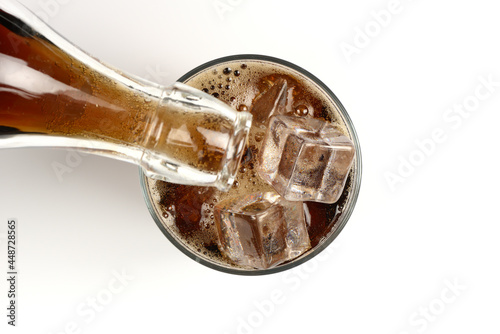Vertiendo bebida refrescante de cola en un vaso con hielos, visto desde arriba photo