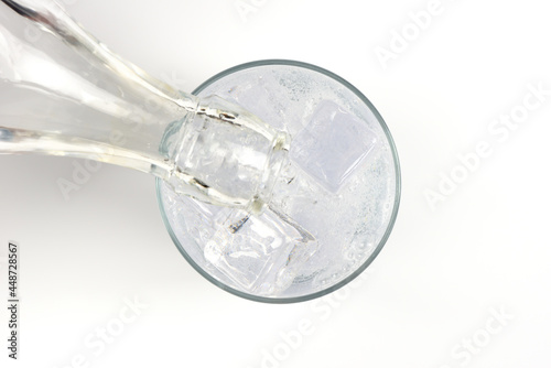Vertiendo bebida refrescante de tónica en un vaso con hielos, visto desde arriba photo
