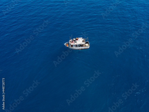 Aerial view of a fishing vessel in the blue sea off the coast of Calabria, Italy © Naeblys