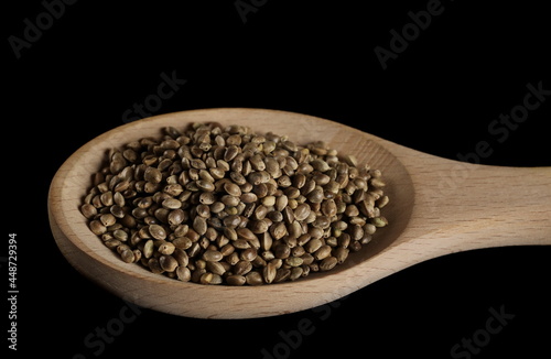 Hemp seeds pile in wooden spoon isolated on black background