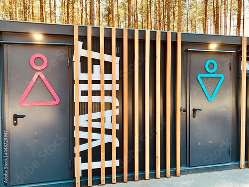 Modern russian street toilet in park in summer day. Writing on the cabin femail and male tualet means Toilet wc sign on the door City toilet. photo