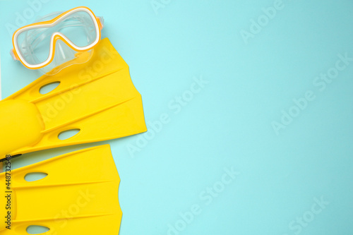 Pair of yellow flippers and diving mask on turquoise background, flat lay photo