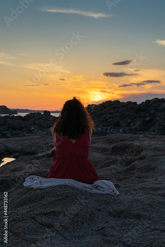 woman sitting on the beach  contemplates the sunset