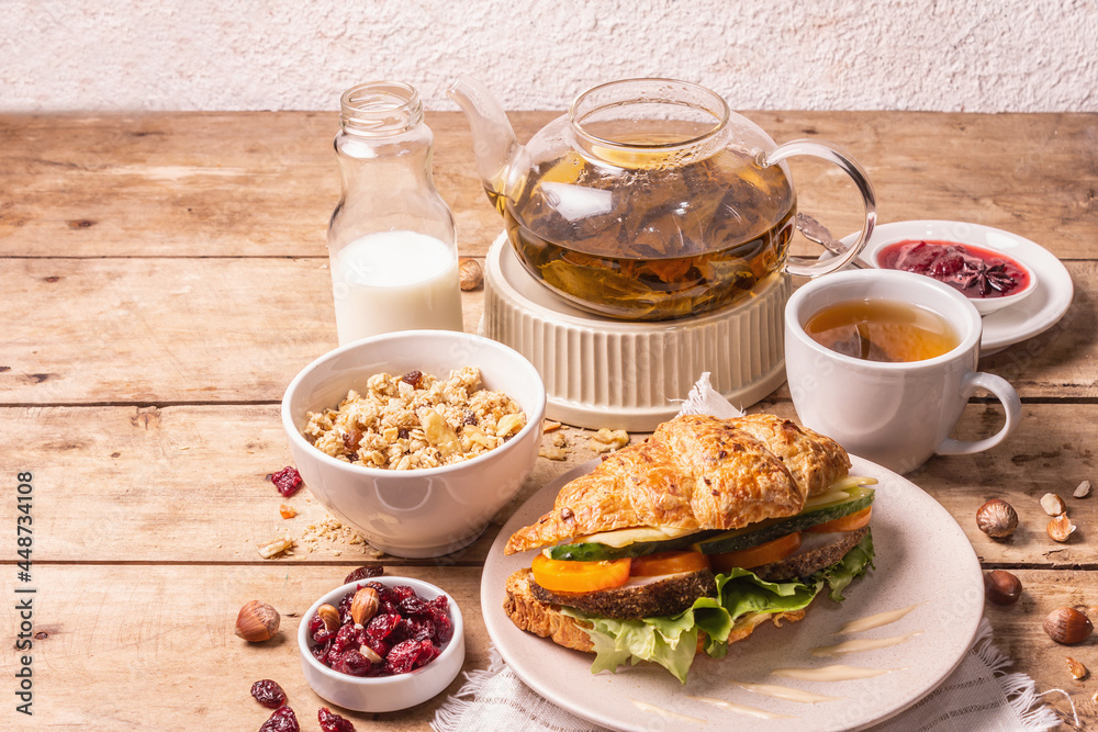 Healthy breakfast concept. Morning good mood with tea, croissant, granola, milk, and jam Healthy breakfast concept. Morning good mood with tea, croissant, granola, milk, and jam