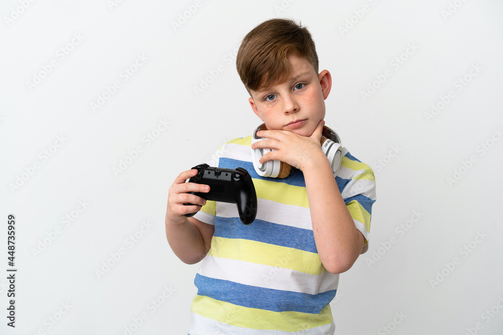Little redhead boy holding a game pad isolated on white background thinking Little redhead boy holding a game pad isolated on white background thinking