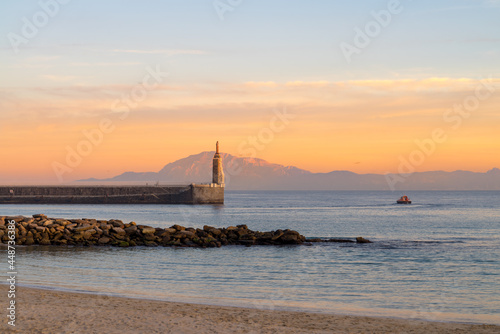 View of Punta del Santo with a boat from a Tarifa Port breakwater, the Morocco Mountains across the Straits of Gibraltar in the distance