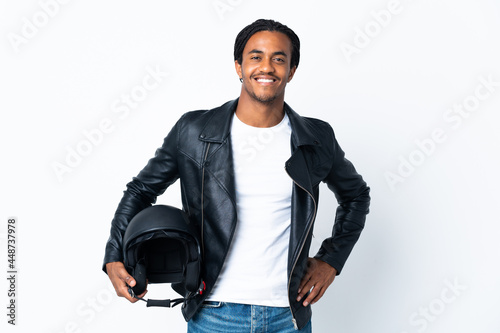 African American man with braids holding a motorcycle helmet isolated on white background posing with arms at hip and smiling