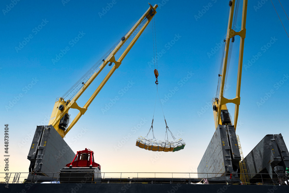 Ship crane lift jumbo sling of sugar bags load into ship hold. Bag cargo loading to ship for export. Ship crane lift jumbo sling of sugar bags load into ship hold. Bag cargo loading to ship for export.