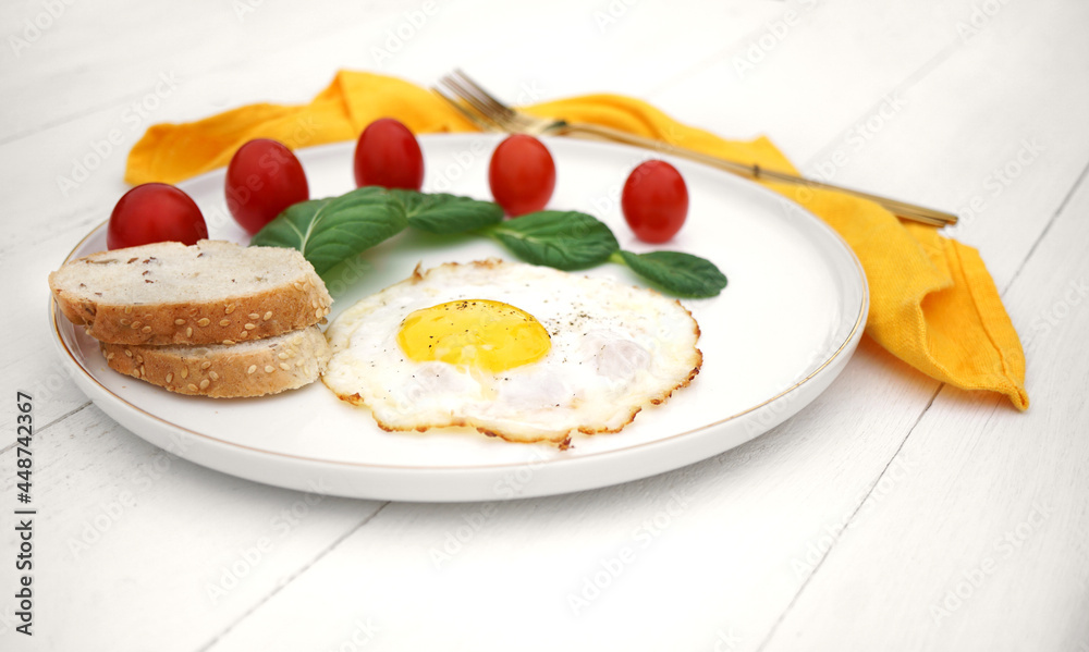 scrambled eggs with lettuce and cherry tomatoes on a white plate with a yellow napkin and golden cutlery scrambled eggs with lettuce and cherry tomatoes on a white plate with a yellow napkin and golden cutlery