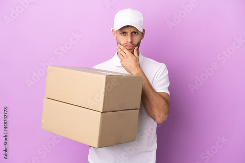 Delivery caucasian man isolated on purple background thinking © luismolinero