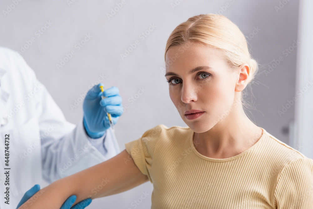 blonde woman looking at camera during vaccination in clinic blonde woman looking at camera during vaccination in clinic