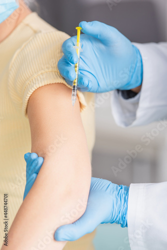 cropped view of doctor in latex gloves vaccinating woman