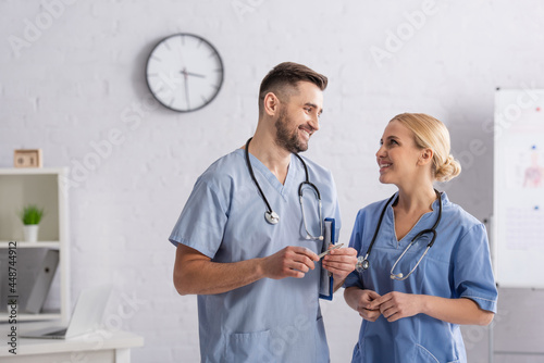 Tablou pe pânză happy doctors in blue uniform looking at each other while talking in hospital