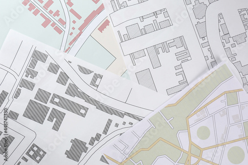 Many different cadastral maps of territory with buildings as background, top view photo