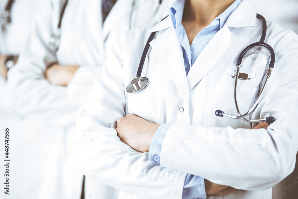 Group of modern doctors standing as a team with arms crossed in hospital office and ready to help patients. Medical help, insurance in health care, best disease treatment and medicine concept Group of modern doctors standing as a team with arms crossed in hospital office and ready to help patients. Medical help, insurance in health care, best disease treatment and medicine concept