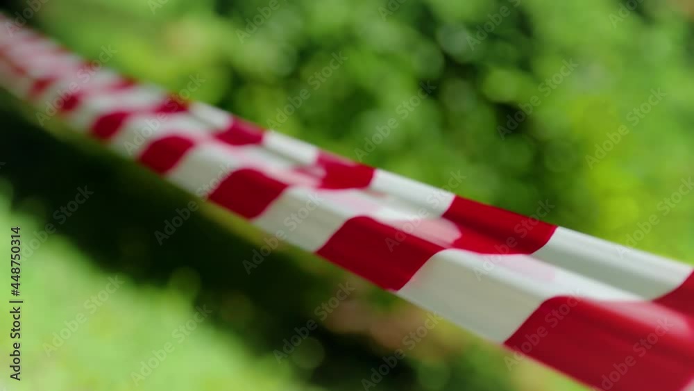 Red and white warning tape stretched across a blurred background with
