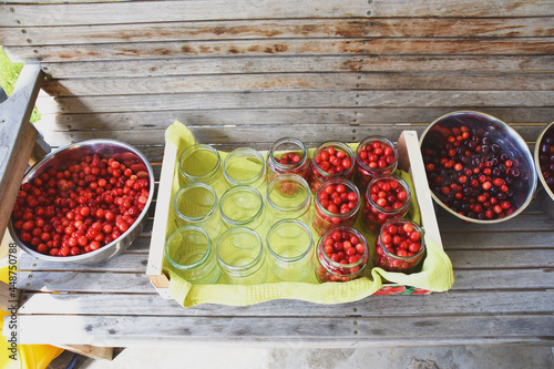 Cherry compote being prepared for winter preservation in a big pot on a stove, where all bacteria is destroyed because of heat.