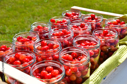 Cherry compote being prepared for winter preservation in a big pot on a stove, where all bacteria is destroyed because of heat.