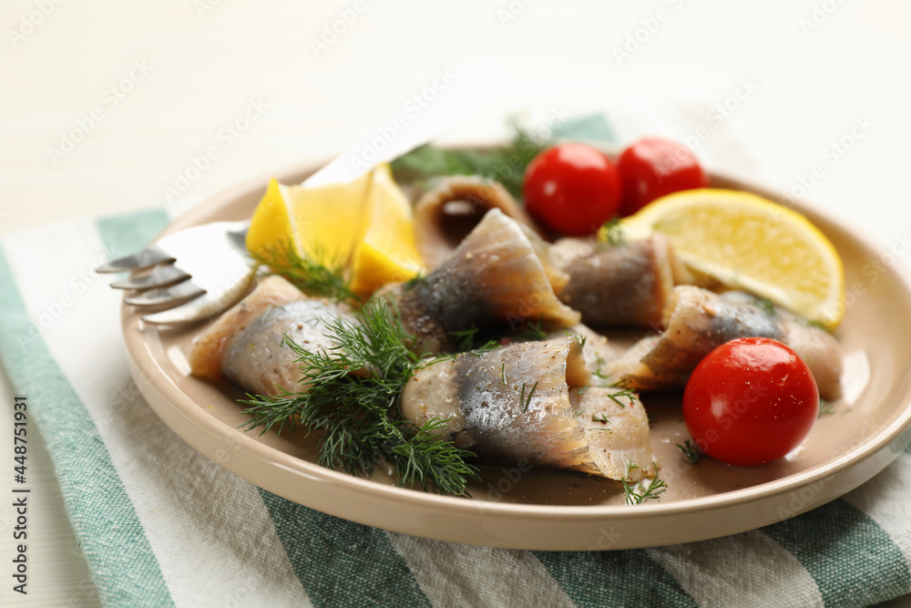 Salted herring fillets served with cherry tomatoes, dill and lemon on light beige table, closeup