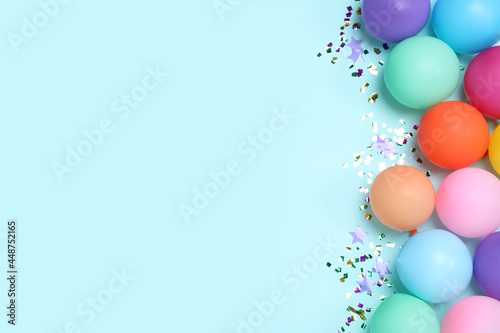 Flat lay composition with balloons and confetti on light blue background, space for text. Birthday decor