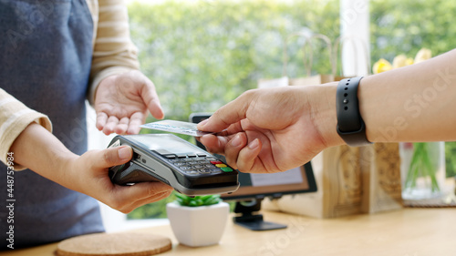 Close-up hand asia woman people work in small sme coffee cafe shop store owner use cashless wifi paywave nfc scan app smart pos reader sale in take out food drink order in urban city life contactless. photo