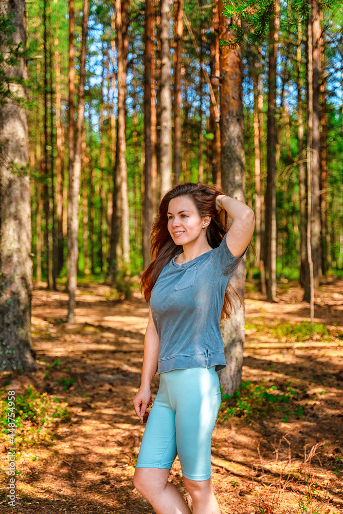 A young athletic woman walks through a pine summer forest A young athletic woman walks through a pine summer forest