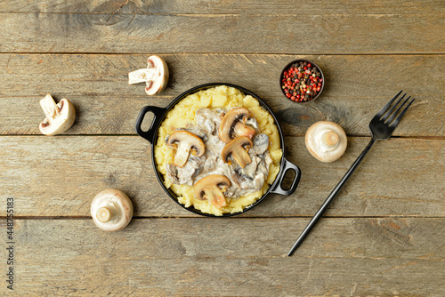 Frying pan with tasty mashed potatoes, mushrooms and peppercorns on wooden background