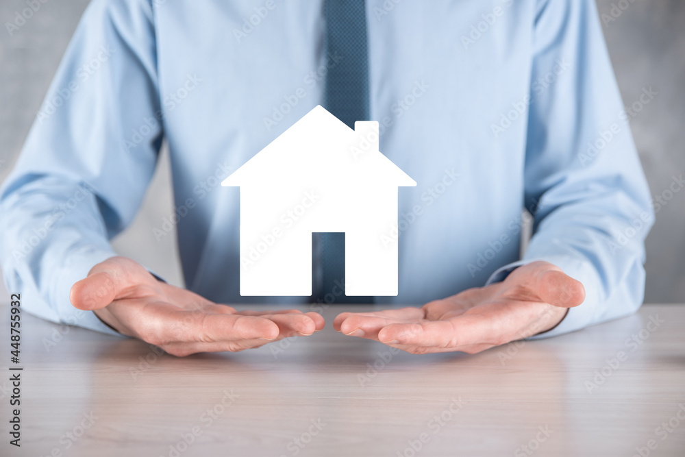 Businessman male hand holding house icon on blue background. Property insurance and security concept.Real estate concept.Banner with copy space. Businessman male hand holding house icon on blue background. Property insurance and security concept.Real estate concept.Banner with copy space.