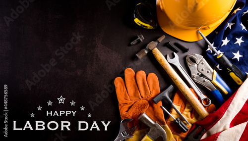 Happy Labor day concept. American flag with different construction tools with the text on dark stone background. © Siam