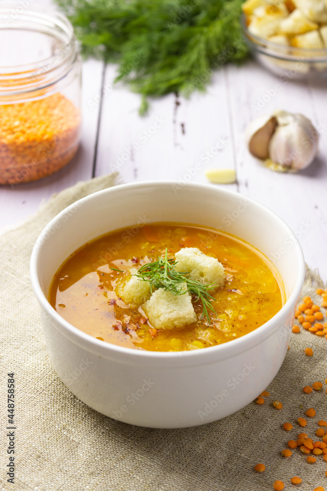 Red lentil soup with ingredients on a light background. Traditional Turkish or Arabic spicy lentil and vegetable soup, healthy vegan food. Side view, vertical orientation. Red lentil soup with ingredients on a light background. Traditional Turkish or Arabic spicy lentil and vegetable soup, healthy vegan food. Side view, vertical orientation.