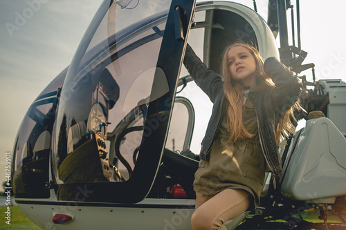 Dreamy tween girl standing near open door of helicopter photo