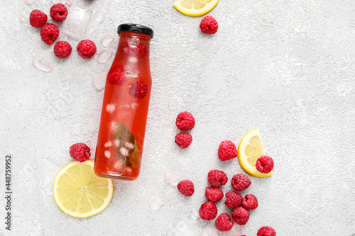 Bottle with tasty raspberry lemonade  on light background photo