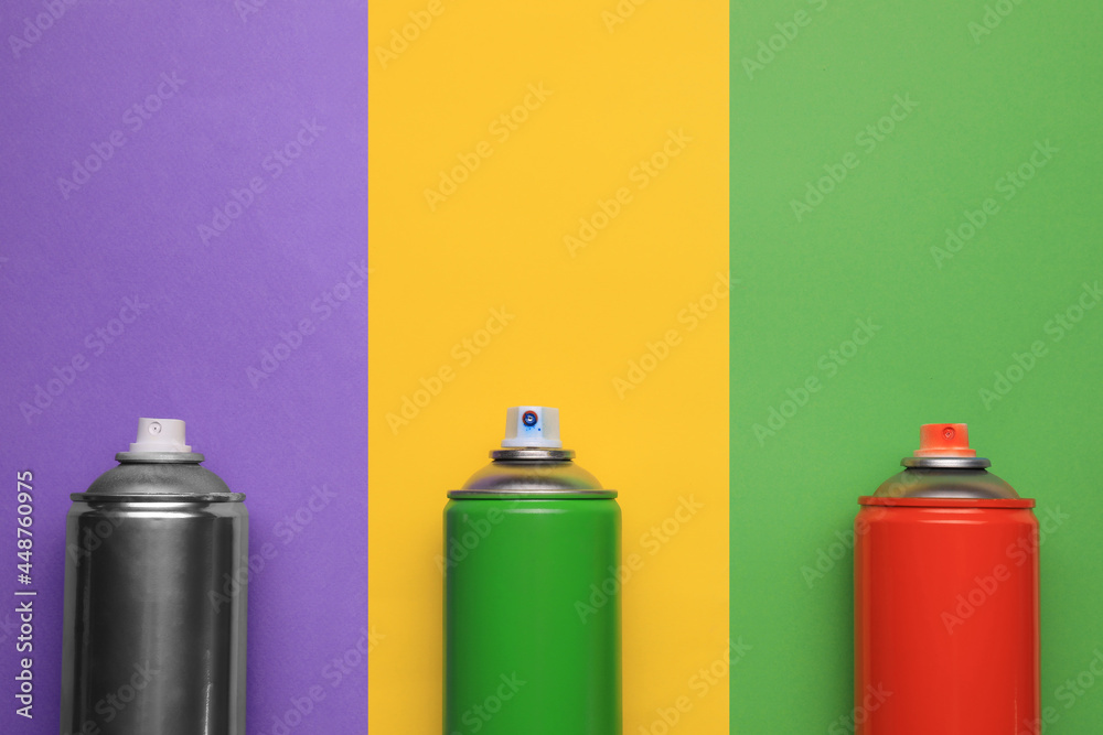 Cans of different spray paints on color background, flat lay with space for text. Graffiti supplies Cans of different spray paints on color background, flat lay with space for text. Graffiti supplies