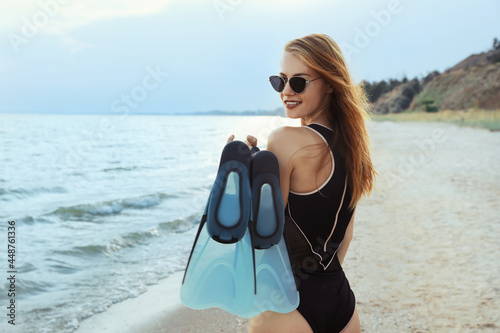 Happy woman with flippers near sea on beach
